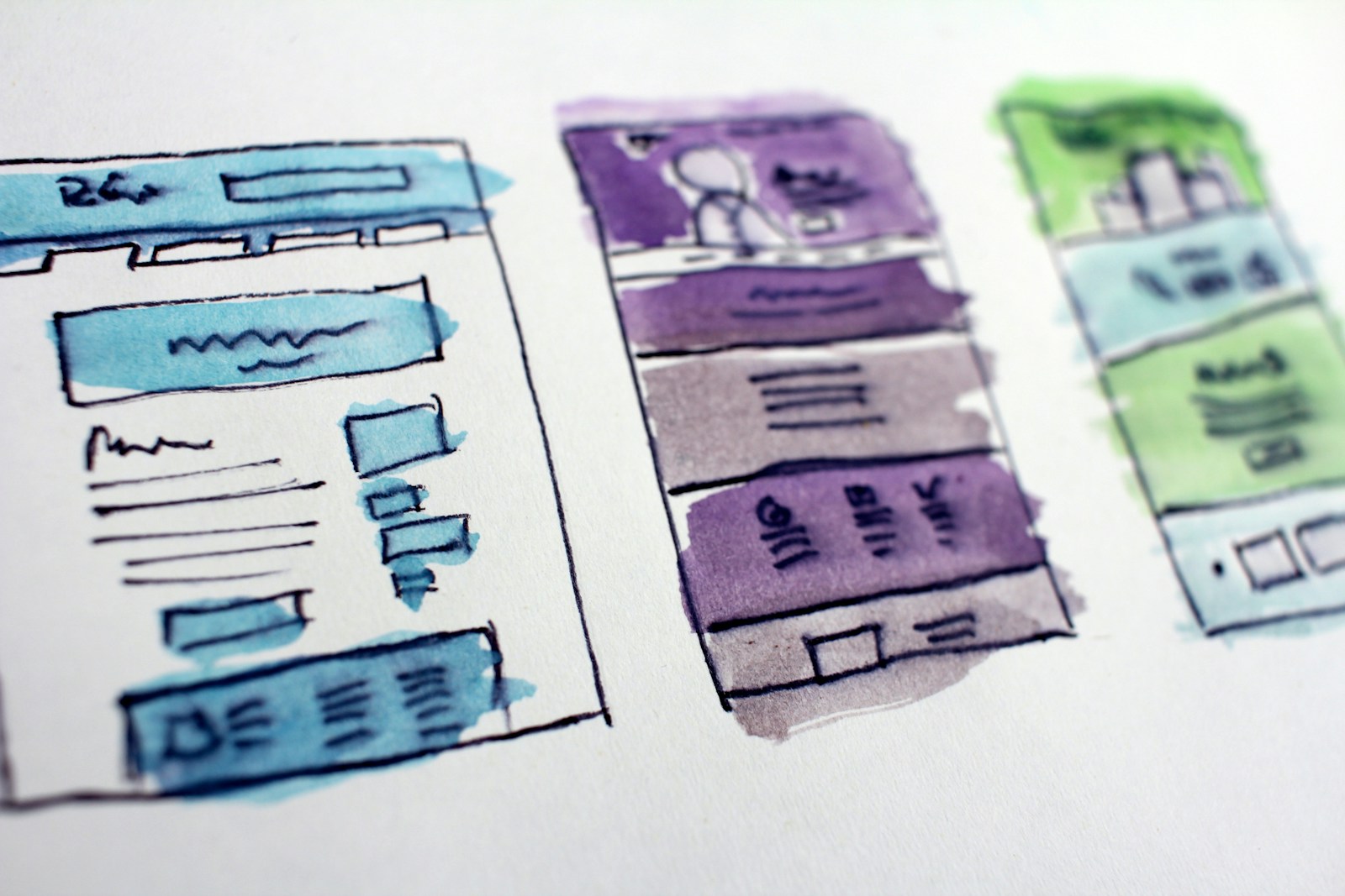 Watercolour wireframe sketches of website layouts on paper